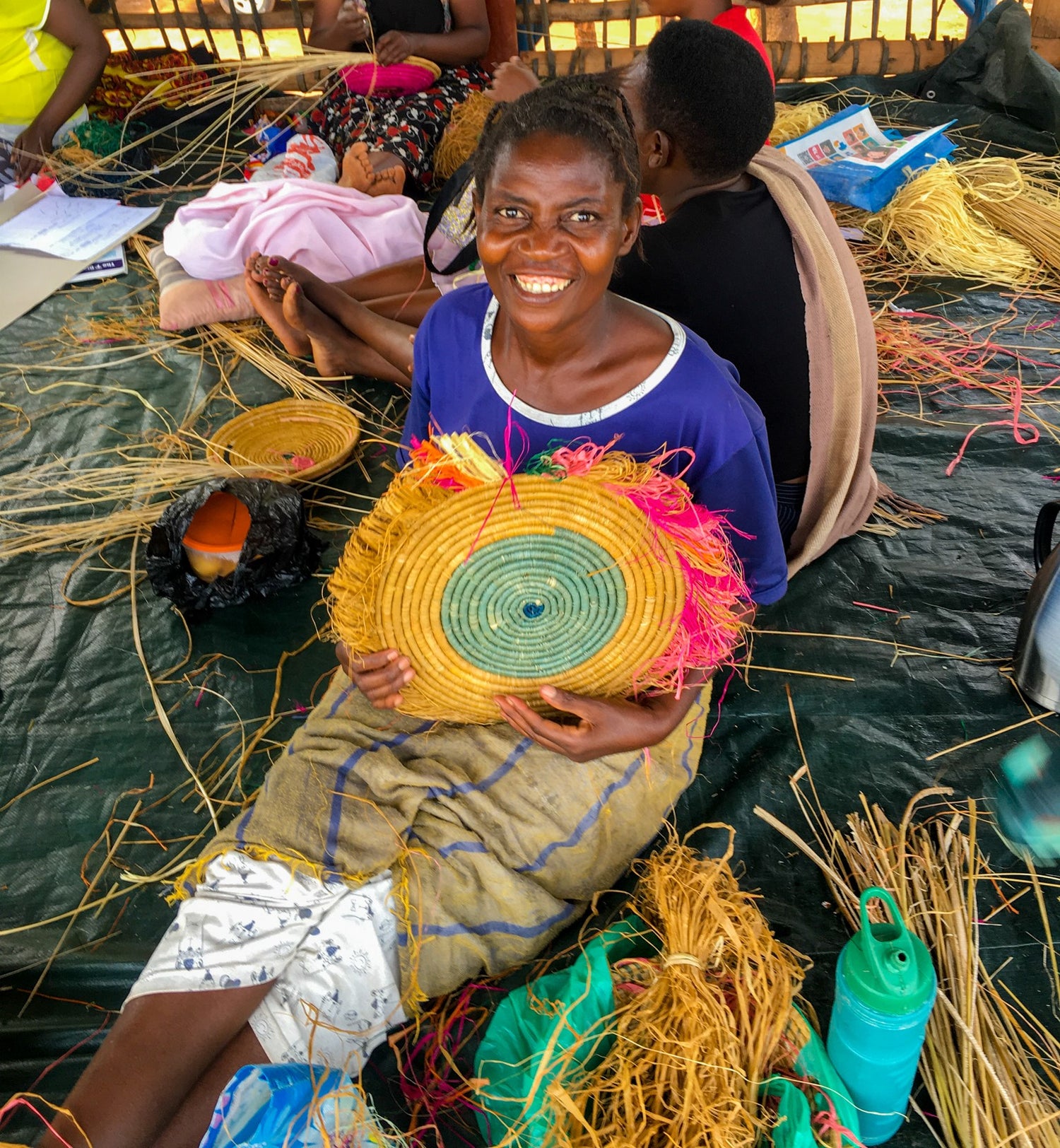 Uganda lady smiling sitting on floor with woven basket