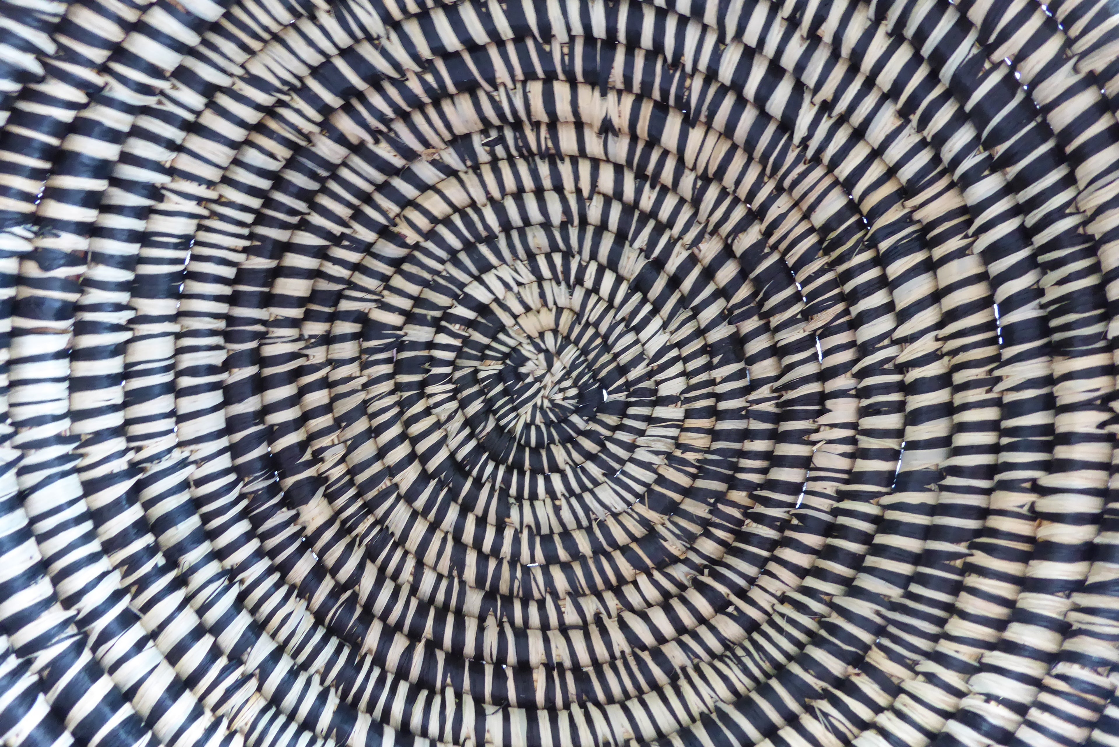 Close up ugandan hand woven basket fruit bowl in black and white